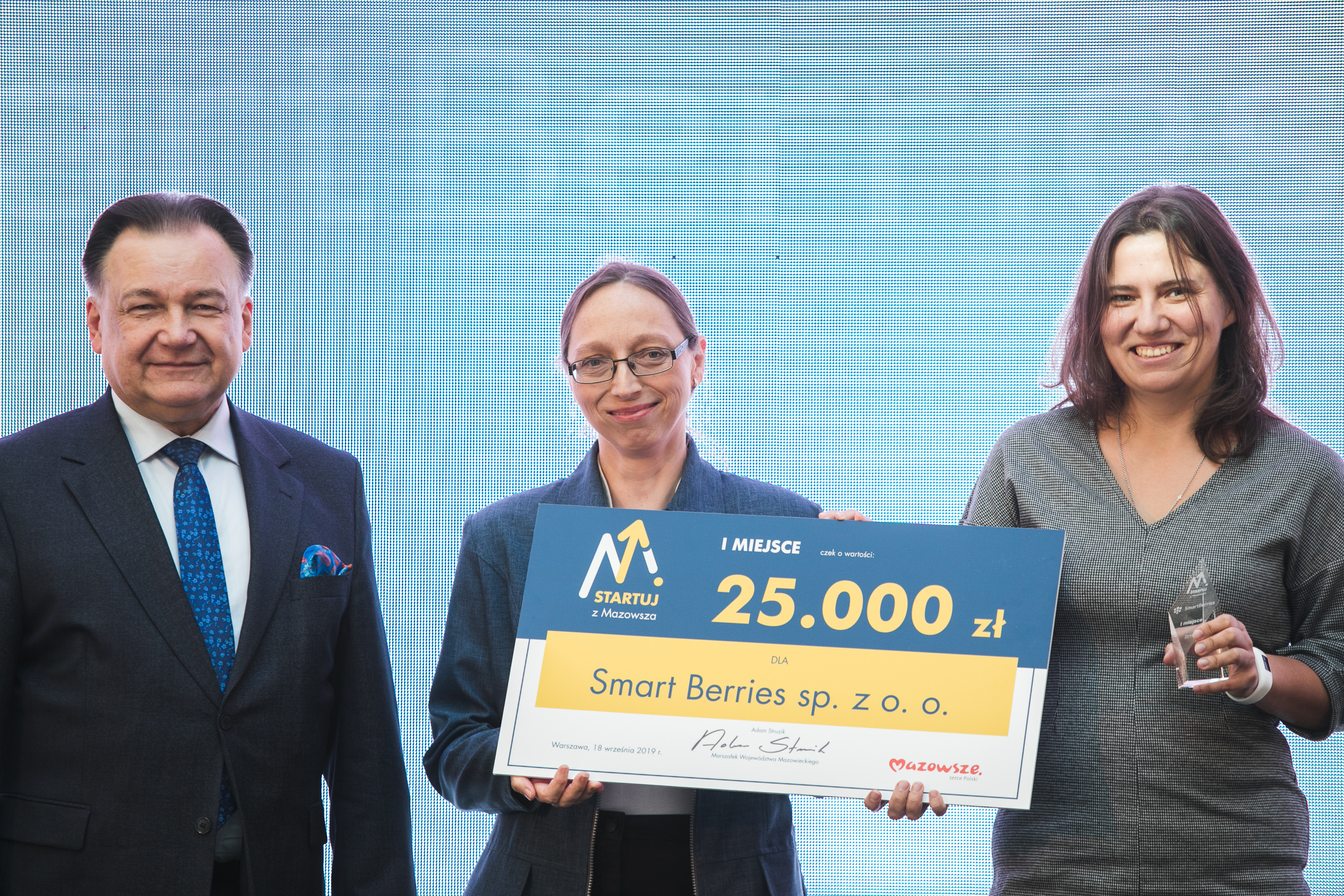 Na zdjęciu od lewej strony Marszałek Województwa Mazowieckiego Adam Struzik i laureatki I nagrody, reprezentantki firmy Smart Berries, trzymające czek na 25 000 złotych.